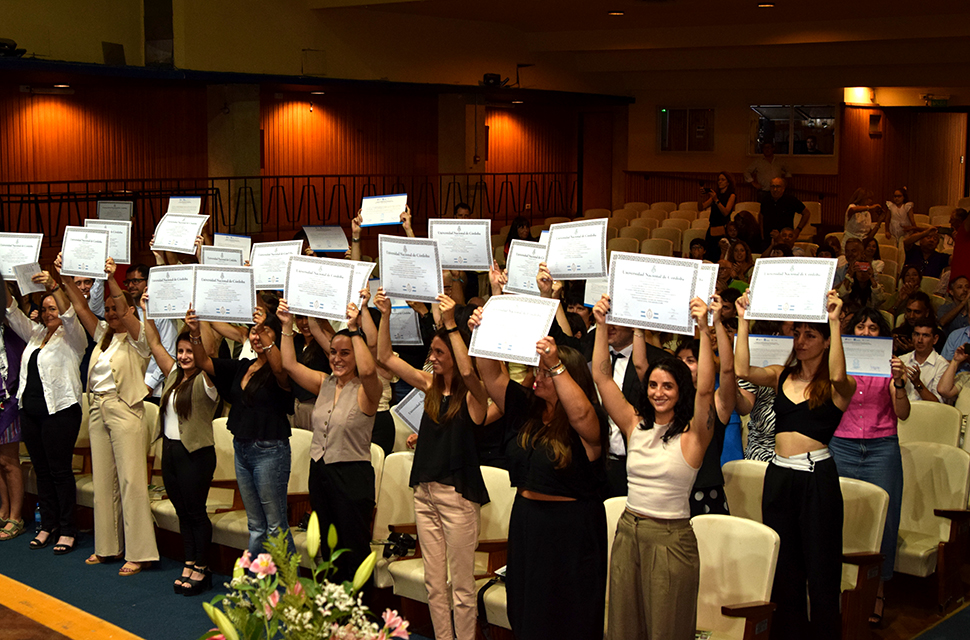 Egresadas y egresados levantando su diploma con los dos brazos en el acto de colación