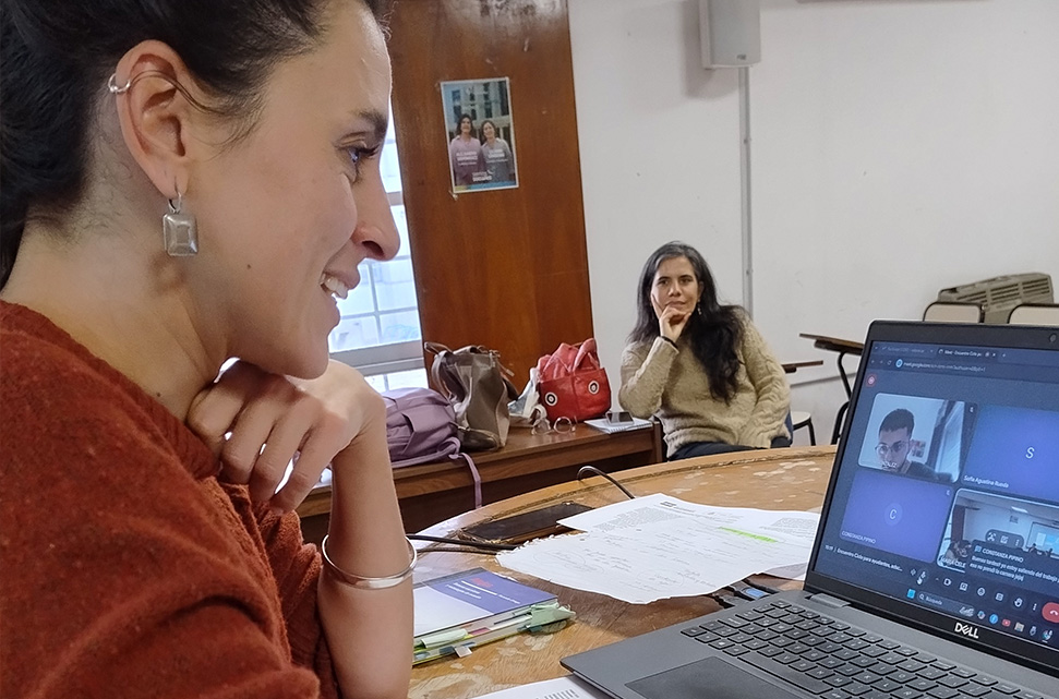 una-mujer-mirando-una-computadora-en-la-que-se-ve-una-reunion-virtual-con-otros-participantes
