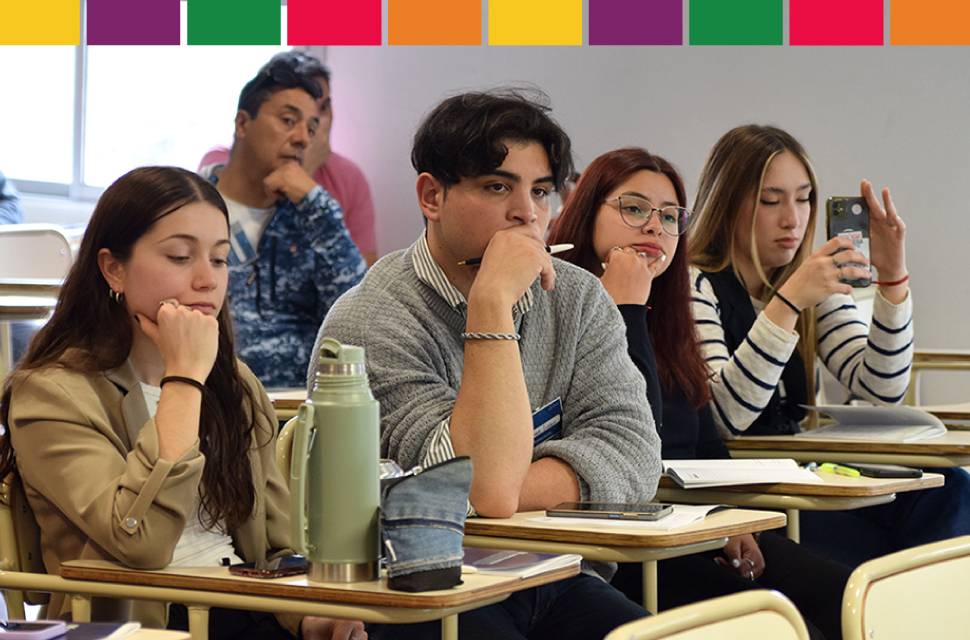 Imagen con varios estudiantes sentados mirando hacia adelante. 