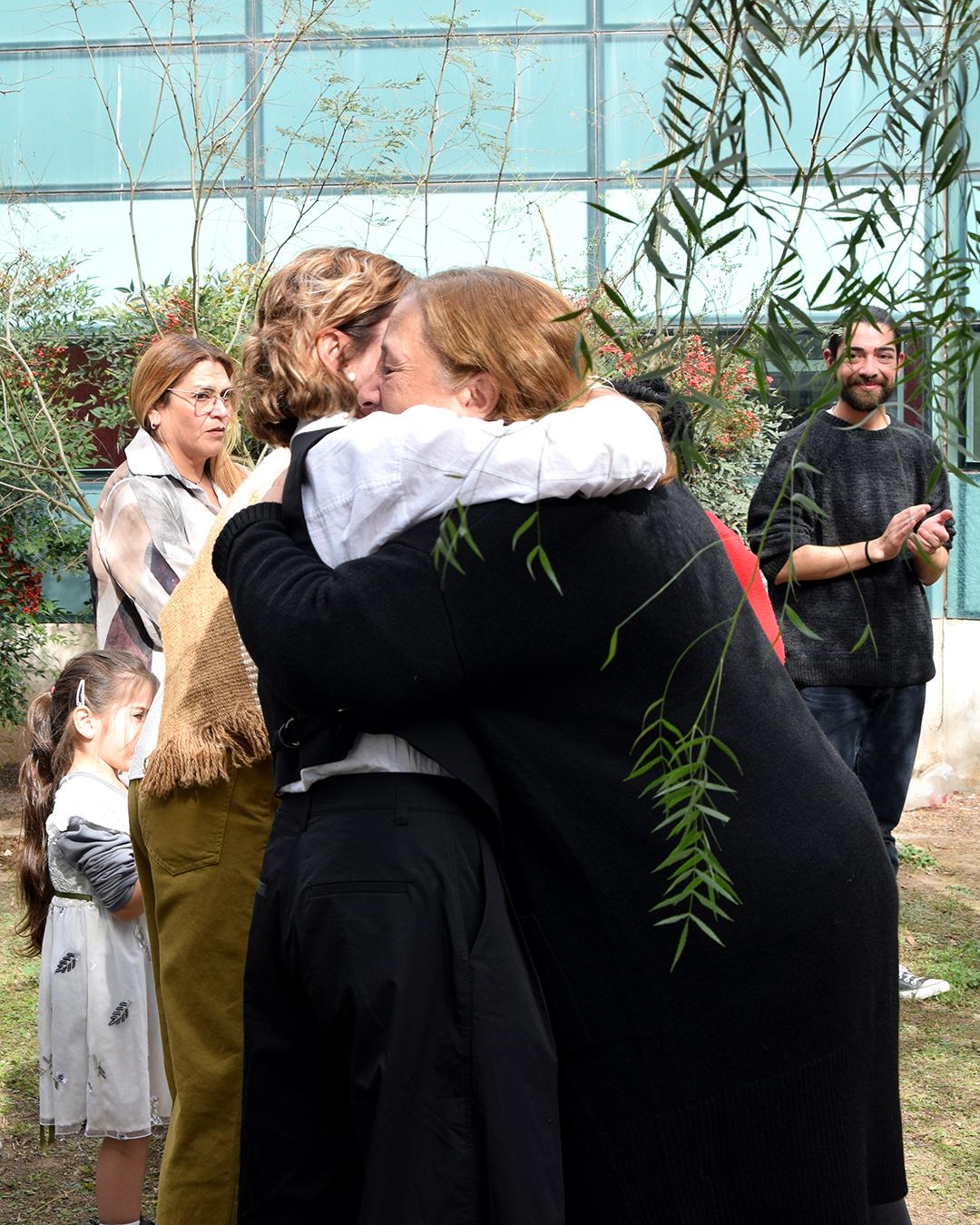 Abrazo entre la vicedecana saliente Jacinta Burijovich y la vicedecana entrante Liliana Córdoba. gente de fondo observndo el abrazo