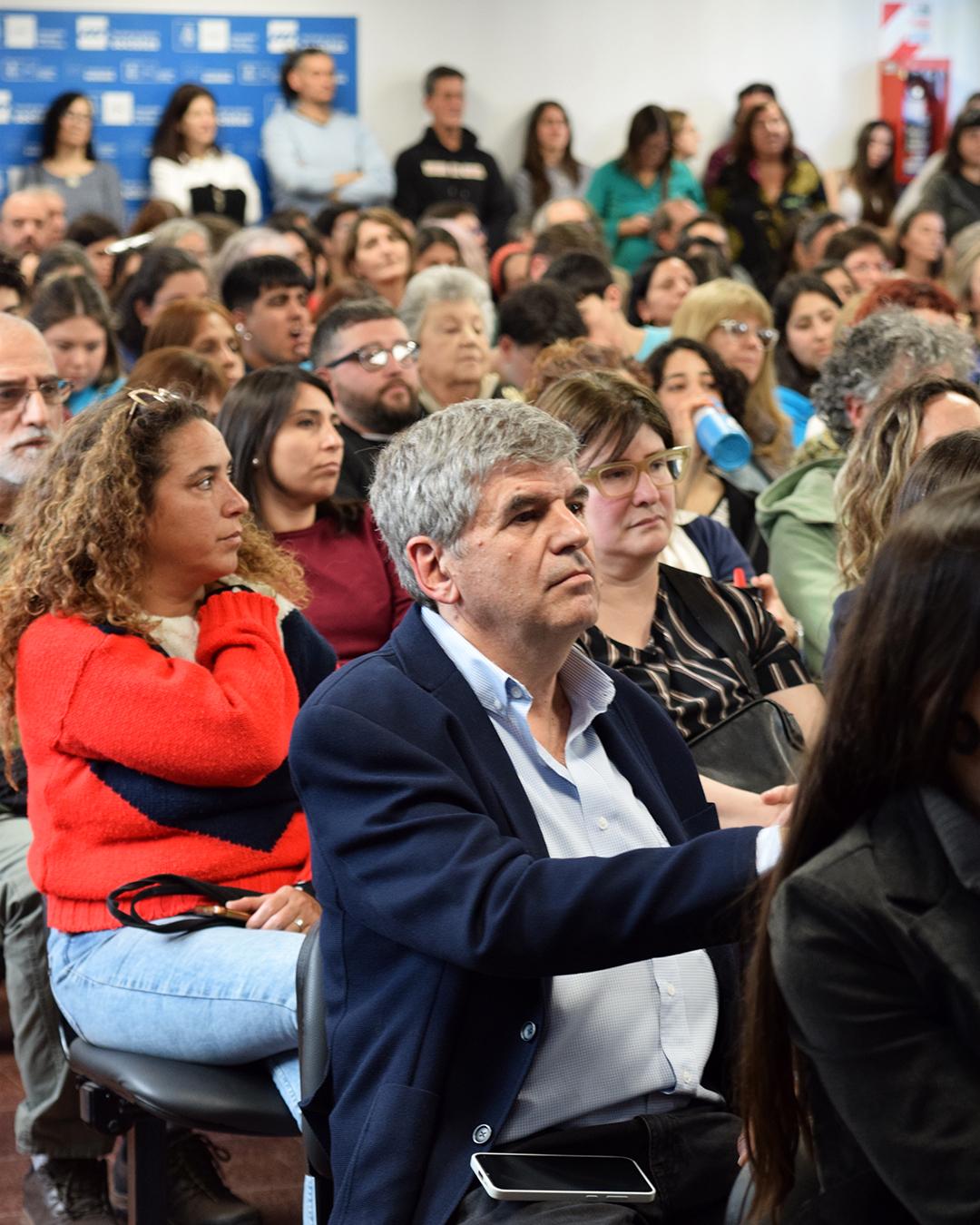 personas senatadas del publico mirando al escenario