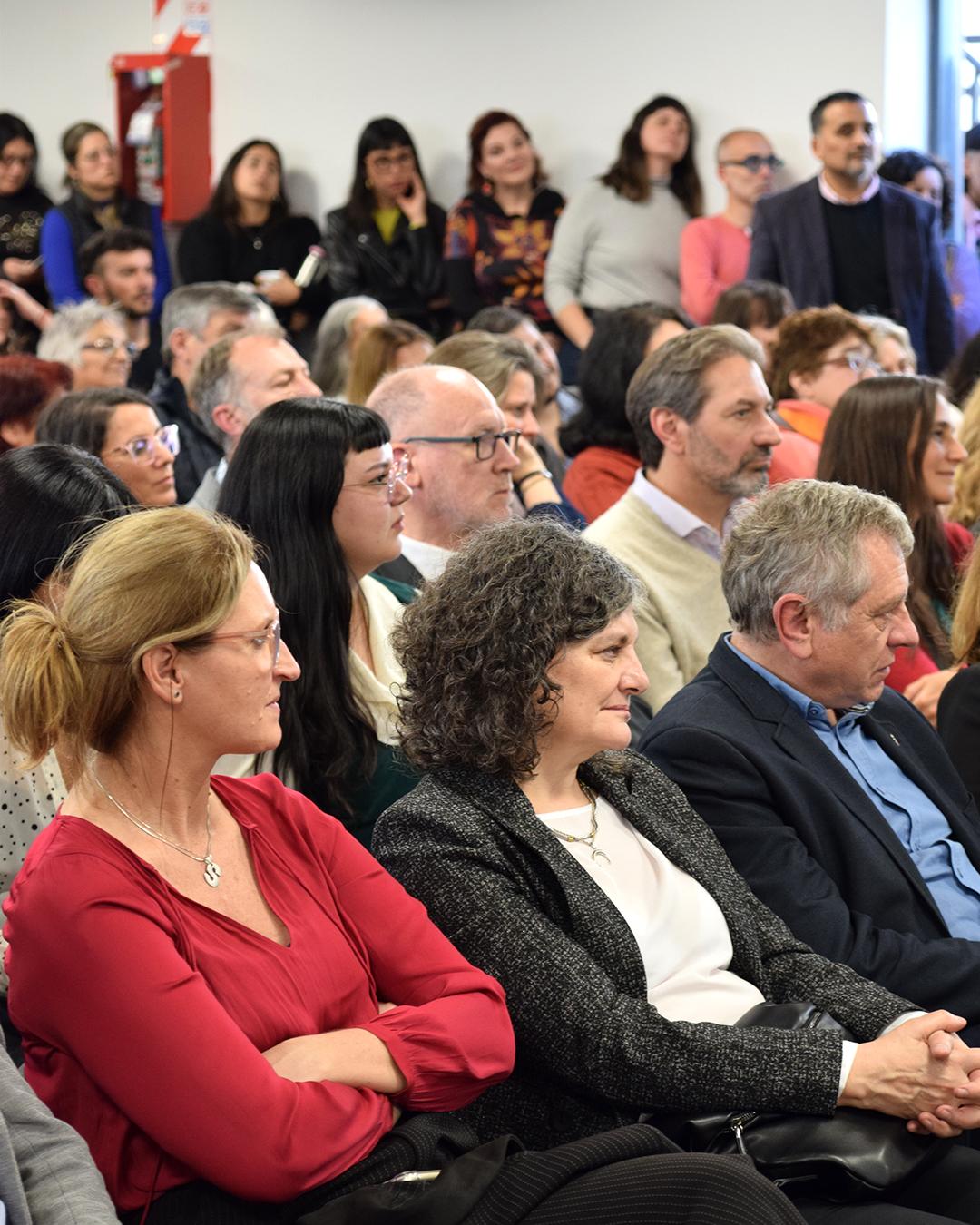 personas sentadas del publico mirando al escenario