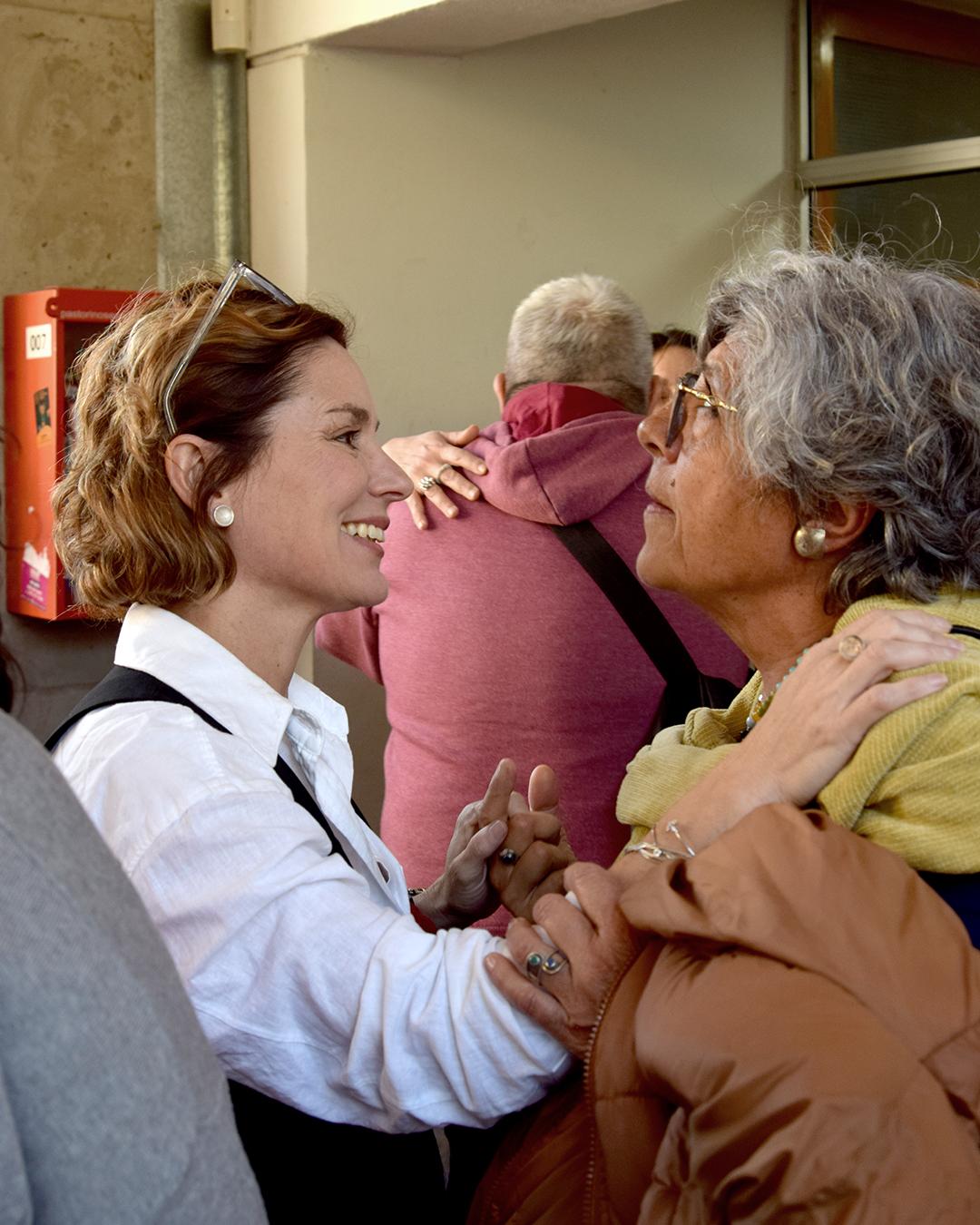 En primer plano dos personas de perfil mirandose de frente, sonriendo