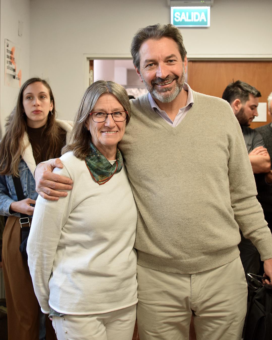 Primer plano dos personas mirando a cámara sonrientes. del lado izquierdo El dipuatado Nacional Pablo Carro abrazando a la secretaria de decanato Adriana Di Lolo