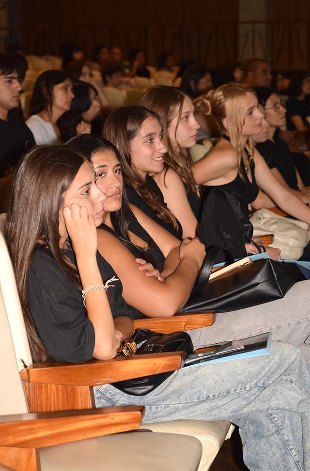 Jóvenes ingresantes sentadas escuchando y mirando a escenario