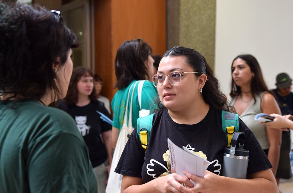 Joven de frente conversando con otra persona de espalda