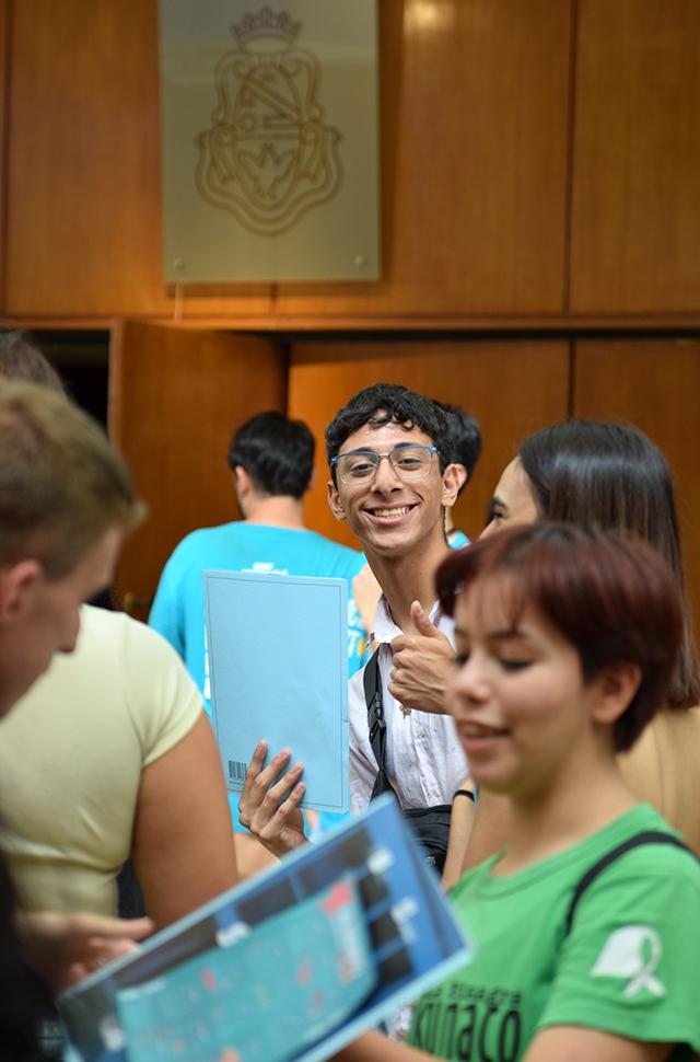 Joven de fondo con gesto sonriente mirando a camara y levantando el dedo pulgar
