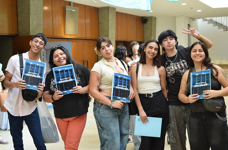 Jovenes posando de ferente, mirando a cámara, sonrientes y mostrando sus carpetas en mano