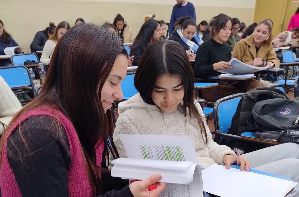 dos-estudiantes-mujeres-leyendo-un-apunte-en-un-aula-en-clase