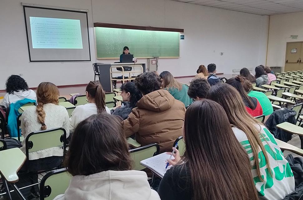 grupo-de-estudiantes-en-un-aula-sentados-en-clase-mirando-hacia-adelante-donde-está-la-docente-sentada