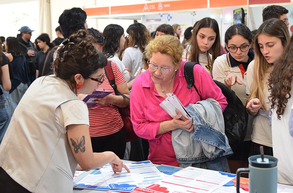 Voluntaria conversando con estudiante de secundario en el stand de sociales