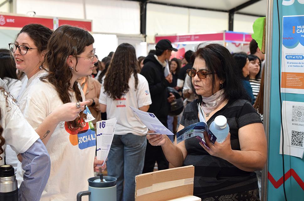 Voluntaria conversando con estudiante de secundario en el stand de sociales