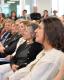 En primer plano de perfil se encuentra la nueva decana electa Alejandra dominguez, de fondo se ven a la decana saliente, vicedecana entrante liliana cordoba, el rector Jhon Boreto y más autoridades, todas de perfil mirando al escenario