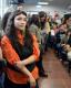 en primer plano una persona mirando al escenario, de fonde hay multitud de personas